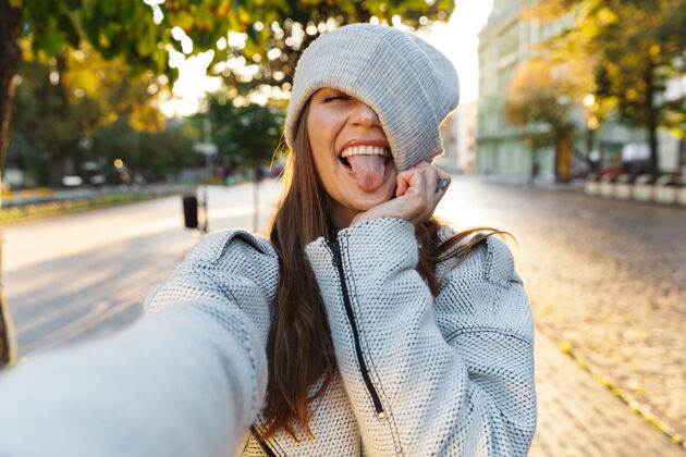 自拍一位穿着秋衣戴秋帽的美丽年轻女子在户外散步 自拍街道休闲照片