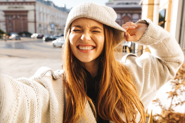 户外快乐的年轻女子穿着秋衣 戴着秋帽 在户外自拍女性微笑照片