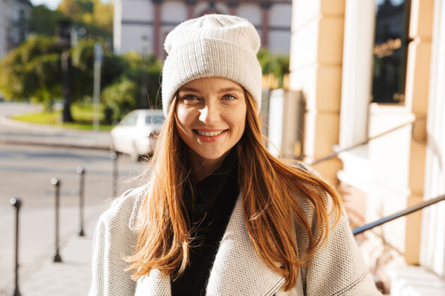 秋天一个穿着秋衣 头戴秋帽 在城市街道上走在户外的快乐的年轻女子外套乐趣女性