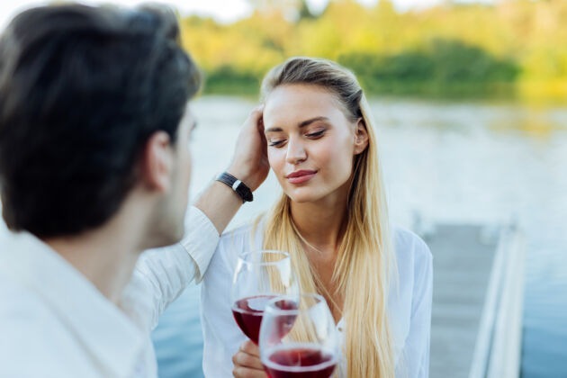 健康体贴的男朋友好体贴的男人抚摸他的女朋友的头发 同时向她表达他的爱放松玻璃关系
