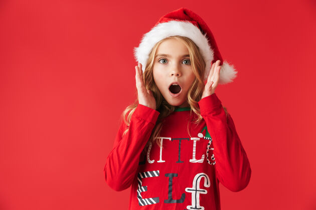 节日震惊的小女孩穿着圣诞服装孤零零地站着惊喜微笑女孩