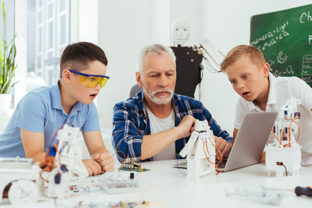 简历这真是太棒了漂亮的小男孩一边看着笔记本电脑屏幕 一边表现出他们的兴奋童年工程成熟