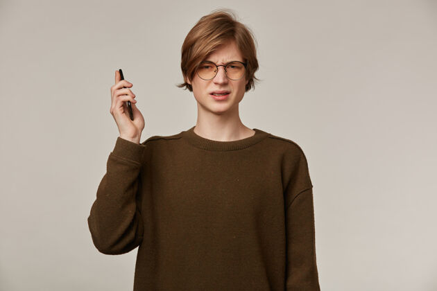 社交帅哥 金发帅哥头发穿着棕色毛衣和眼镜支撑手机单身外表