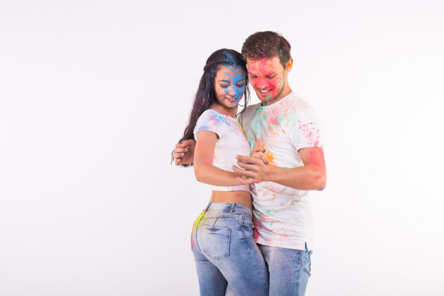 娱乐友谊 社交舞蹈 爱情 胡里节 人的概念-年轻夫妇玩颜色和舞蹈巴查塔或kizomba在胡里节在白色表面复制空间油漆家庭女人