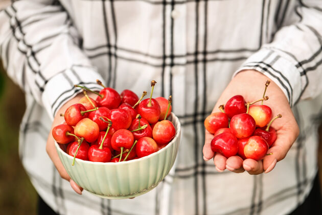 碗在花园里拿着一碗甜樱桃的女人 特写镜头食物产品健康