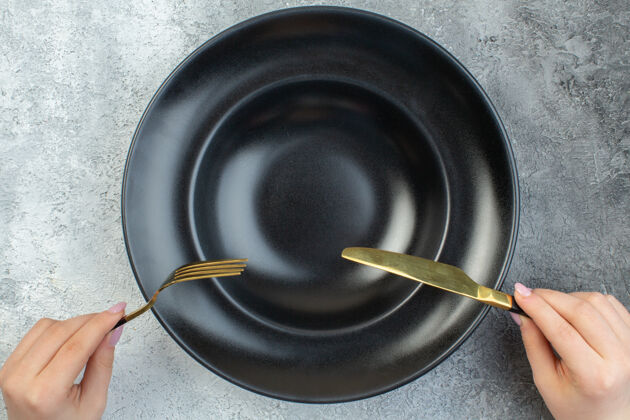 声音手持优雅的叉子和刀在黑色餐具上设置在孤立的灰色冰面与自由空间炊具金属锅