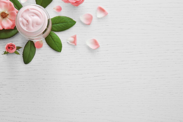 护理面霜和粉红色的花在白色的木头上草药药房花