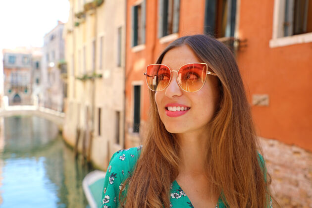 年轻人快乐迷人的女人在意大利威尼斯微笑太阳镜运河壁板