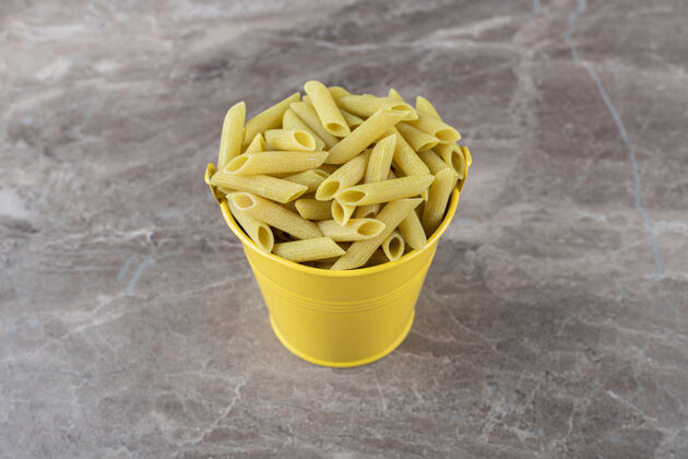 佩恩黄色桶里的意大利面 放在大理石表面上美味美味碳水化合物