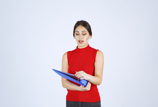 工人穿着红衬衫的女孩手里拿着一个蓝色的商业文件夹年轻人项目任务