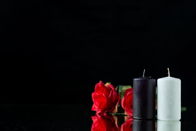 黑暗一對蠟燭的正面圖 黑色上有紅玫瑰花瓣死亡玫瑰