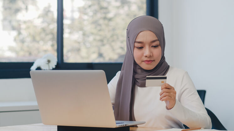 学习亚洲女士使用笔记本电脑 信用卡购买和电子商务网上购买办公室阿拉伯语个人购物