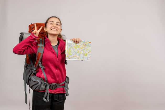 旅游正面图：年轻的旅行者背着大背包拿着地图示意ok标志持有旅游肖像
