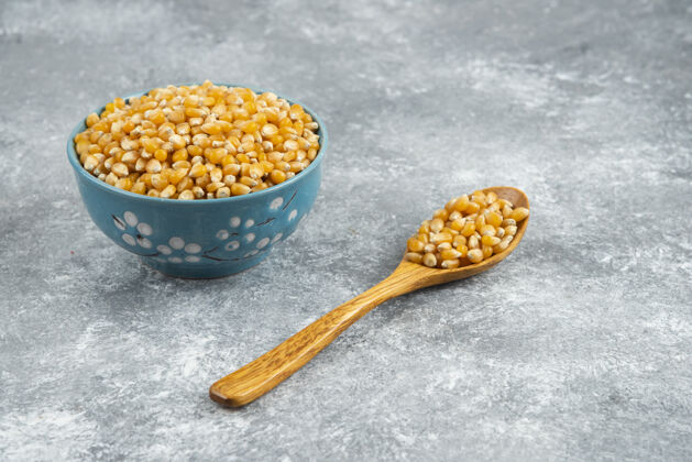 谷类把一堆生玉米种子放在蓝色的碗和木勺里爆米花生的堆