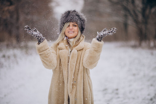 森林美丽的女人在满是雪的公园里散步波西米亚微笑毛衣