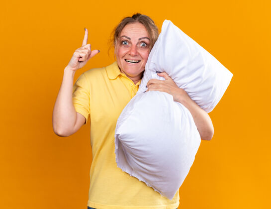目录一个不健康的女人穿着黄色衬衫 患流感 抱着枕头 站在橙色的墙上微笑 感觉好多了微笑拥抱痛苦