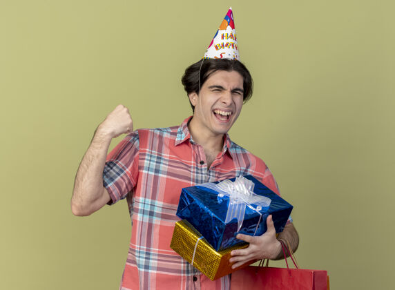 复制快乐英俊的白人男子戴着生日帽 手拿礼品盒和纸购物袋礼物帽子快乐