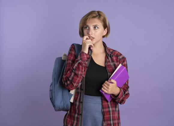 女孩焦急的年轻斯拉夫学生女孩穿着背包咬指甲拿着书和笔记本学生紫色复制