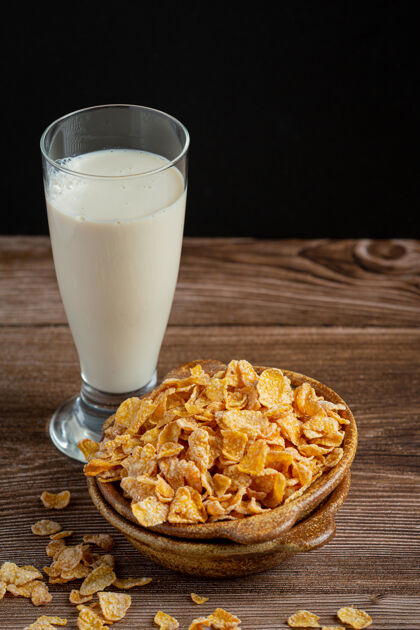 玻璃碗里的麦片和牛奶放在深色的木制背景上玉米麦片白色