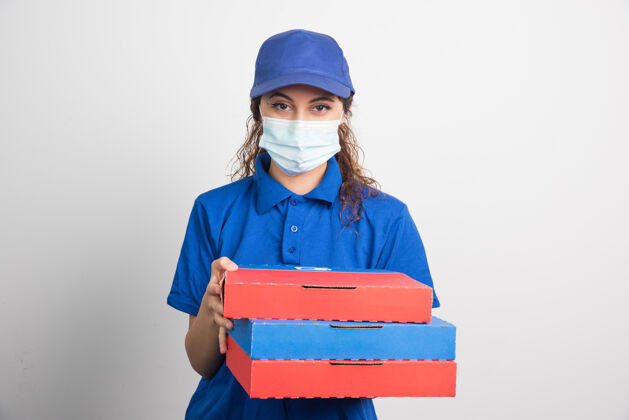 帽子送比萨饼的女孩手里拿着三盒白色的医用面膜食品展示美味