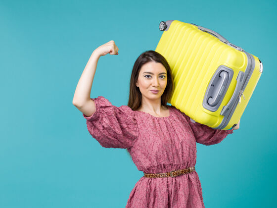 人正面图：年轻女子带着她的黄包在蓝色的背景上度假夏天的旅程人类女人海年轻的女人美丽人