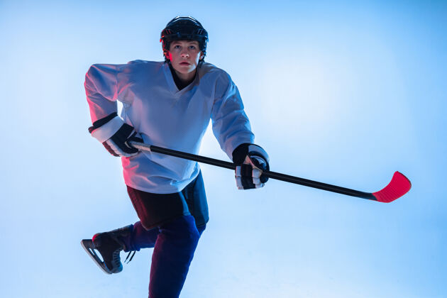 人年轻的男性冰球运动员在霓虹灯下用棍子粘在白墙上动作比赛健康