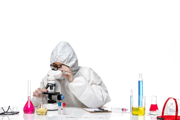 医生正面图身着特殊防护服的年轻女化学家正在用显微镜观察浅白色背景的化学实验室病毒特殊化学人