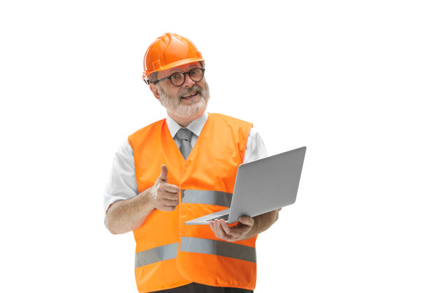 工头一个穿着建筑背心 戴着橙色头盔 带着笔记本电脑的建筑工人项目工程人员