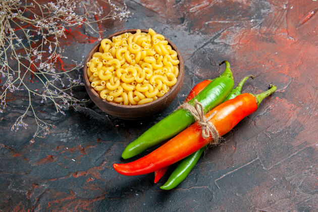 晚餐不同颜色和大小的生面团和辣椒的俯视图 在混合色背景上用绳子绑在一起绳子背景蔬菜