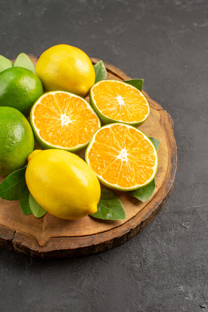 多汁前视图新鲜酸柠檬在黑暗的办公桌树上酸橙水果柑橘柑橘健康食物