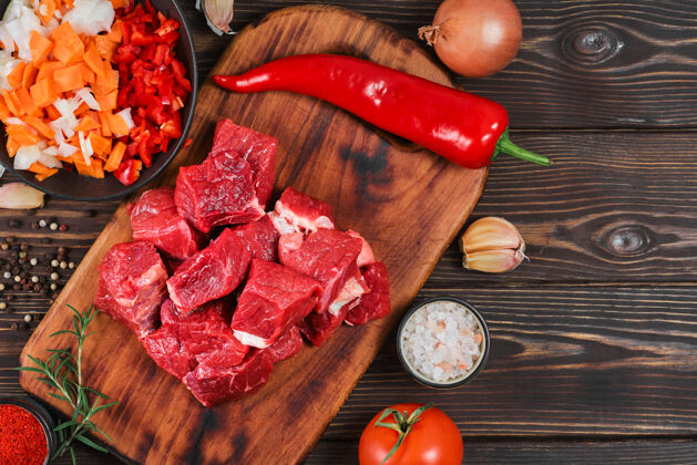 番茄在乡村的木桌上布置烹饪炖肉或炖肉的配料生牛肉 蔬菜 香料传统食物肉汁
