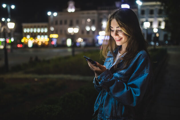Young年轻的白种女人晚上在城里发手机短信Mobile女性使用