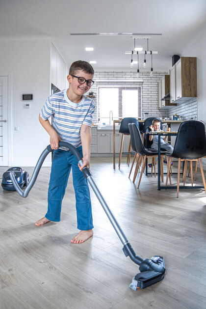 人一个戴眼镜的小男孩用吸尘器打扫房子地板房间管