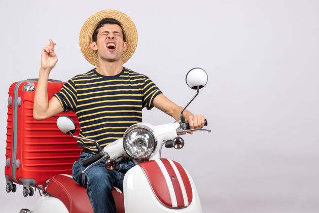 年轻人一个戴着草帽的年轻人坐在轻便摩托车上许愿愿望前面帽子