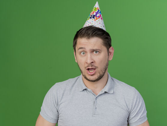 生日困惑的年轻人戴着生日帽孤立在绿色派对绿色派对困惑