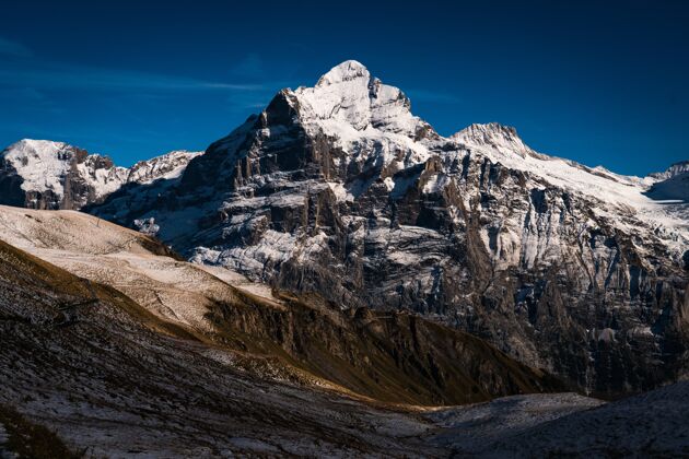季节瑞士晴朗的蓝天下 高高的落基山脉覆盖着白雪山岩石冰