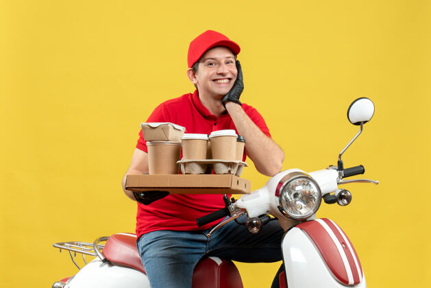 摩托车一个身穿红色上衣 戴着帽子 戴着手套 戴着医用口罩 面带微笑 满怀希望的快递员坐在滑板车上 手里拿着订单面罩滑板车微笑