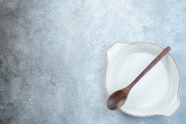 早餐木勺放在白色的空汤盘上 表面呈半暗-浅灰色表面碗空的