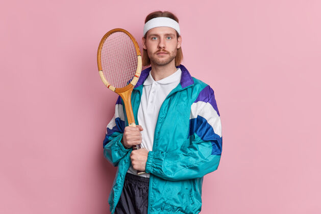 活动照片中严肃的男子拿着网球拍看起来很自信穿着运动服吹嘘自己的运动成绩练习网球技巧取得了最佳成绩比赛冠军严肃男人白种人