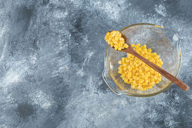 收获用木勺把一堆甜玉米放在玻璃碗里农业木材勺子