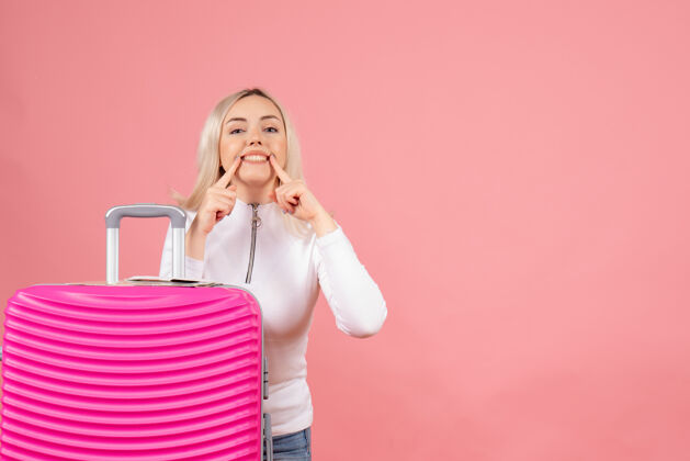 肖像正面是一位漂亮的女士 带着粉红色的手提箱 微笑着指着她时尚休闲指向