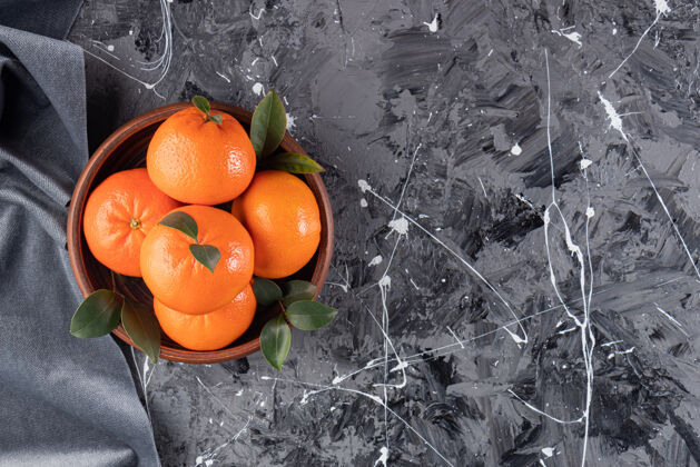 素食整个新鲜的橙色水果和叶子放在木碗上完美成熟水果