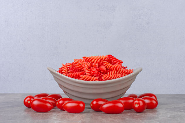 烹饪把生的红色意大利面放在番茄旁边的碗里 放在大理石表面滋补干燥营养