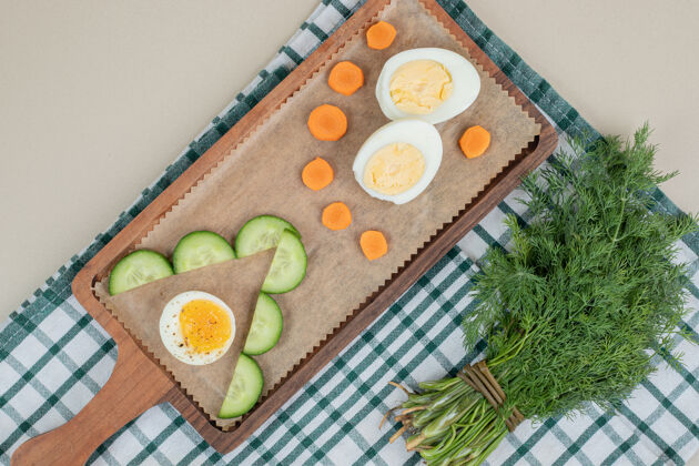 食物有黄瓜片和煮鸡蛋的木制砧板桌布胡萝卜切片
