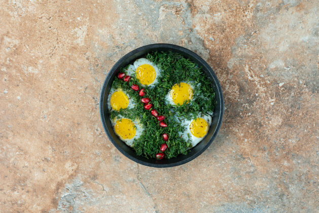 煎蛋卷带煎蛋卷和绿色蔬菜的深色平底锅俯视图大理石蛋黄平底锅