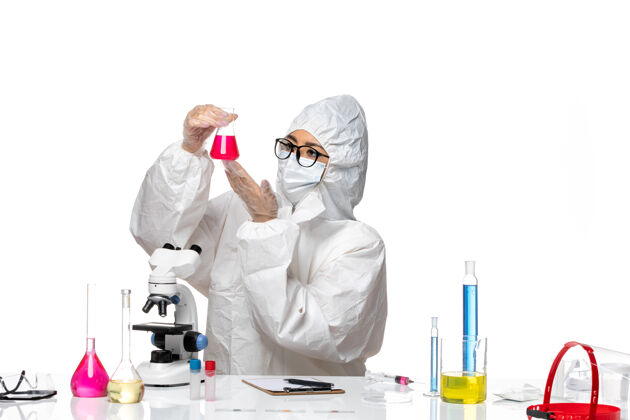 专业前视图穿着特殊防护服的女化学家拿着浅白色背景上的红色溶液-化学病毒实验室套装前面化学