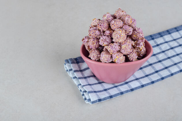 香精放在折叠整齐的毛巾上的小碗 放在大理石桌上的爆米花糖甜味剂糖果碗