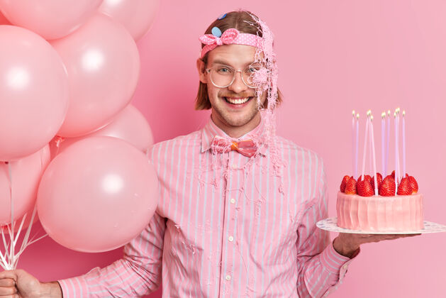 高兴笑容可掬的成年男子涂上蛇纹石喷雾享受生日聚会庆祝周年头带眼镜欢呼