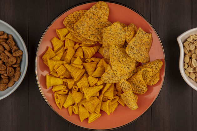 碗木桌上碗上放着松子的橘子盘上的香脆薯片俯视图小吃美味顶部