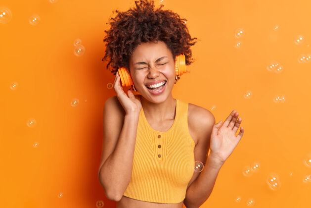 女性美丽快乐的黑皮肤少女通过耳机听音乐闭上眼睛 笑容满面女孩情绪喜悦